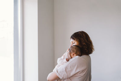 Portrait of happy mum holding infant child on hands.