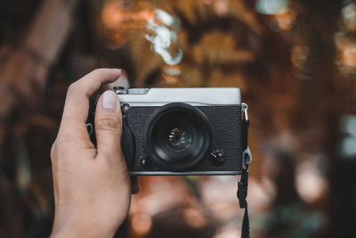 Cropped hand of person photographing with camera outdoors