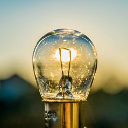 Close-up of light bulb hanging against sky