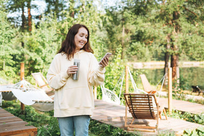 Portrait of smiling young woman standing against plants