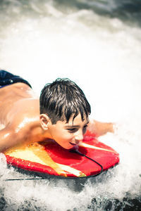 Happy boy surfing in sea during sunny day