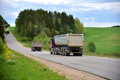 Dump truck on road amidst trees against sky. lorry the transportation of the sand from open pit.