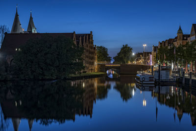 Buildings reflection in trave river against blue sky at night