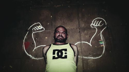 Optical illusion of angry man flexing muscles against wall at night