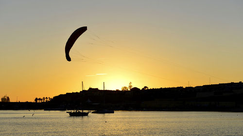 Silhouette people by sea against clear sky during sunset