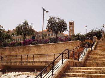 Low angle view of steps amidst buildings against clear sky