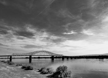 View of bridge over calm sea against cloudy sky