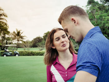 Couple talking while standing in park against sky