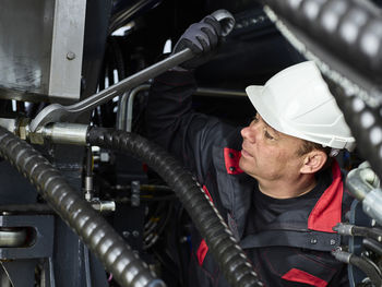 Worker fixing hose line with screw wrench