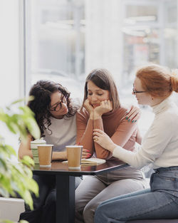 Friends consoling woman in cafe