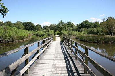 Footbridge over lake against sky