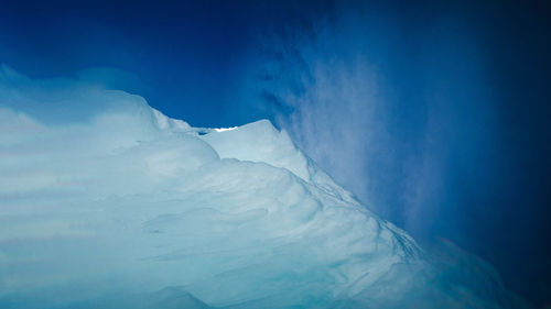 Snow covered landscape against blue sky