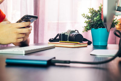 Midsection of man using mobile phone on table