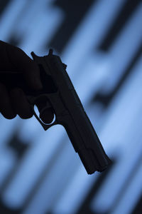 Close-up of hand holding cross against blurred background