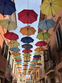 Low angle view of colorful umbrellas hanging against buildings in city