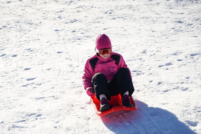 High angle view of girl sledding on snow covered land
