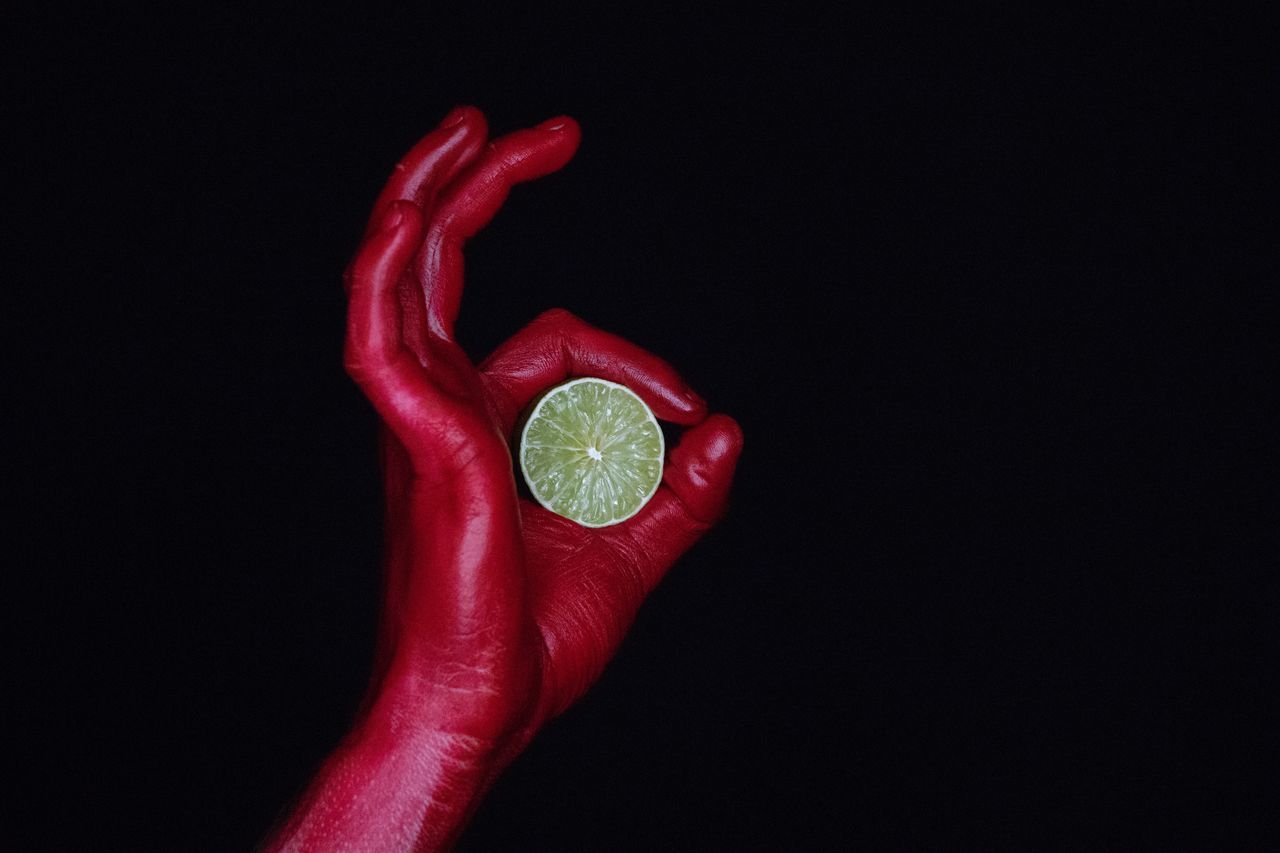 studio shot, red, healthy eating, black background, fruit, indoors, food, food and drink, human hand, copy space, hand, freshness, human body part, citrus fruit, vegetable, holding, one person, close-up, wellbeing, lemon, finger
