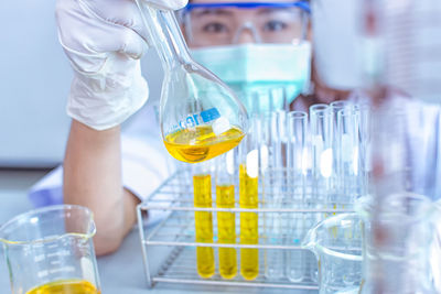 Portrait of woman holding beaker by test tube rack on table