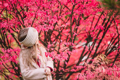 Low angle view of woman standing by pink flowering tree