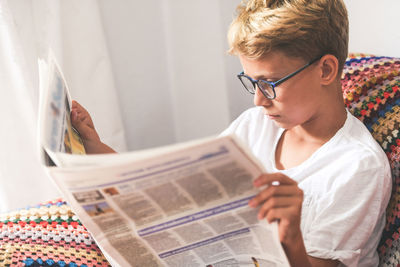 Boy reading newspaper at home