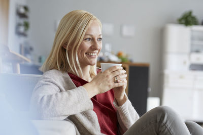 Happy woman relaxing at home, drinking coffee