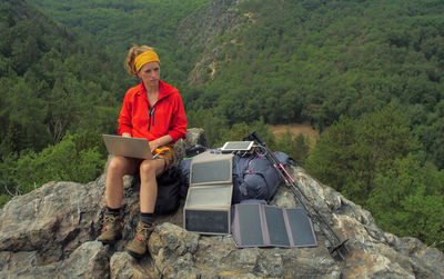 Full length of young woman sitting on rock