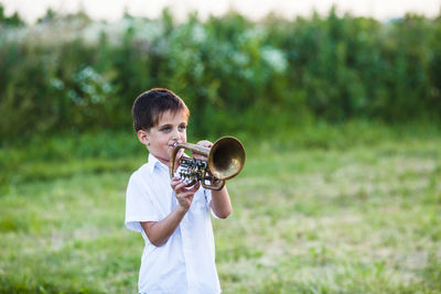 Smiling boy playing trumpet outdoors