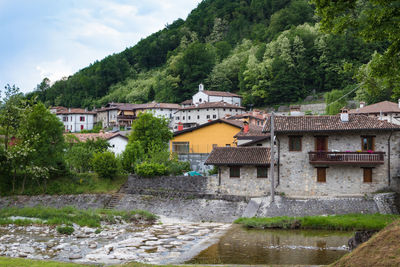 Buildings by river against sky