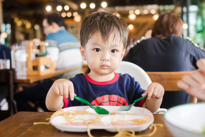 Cute baby boy having meal at restaurant