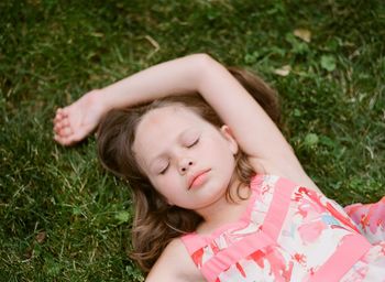 High angle view of cute girl lying on grassy field