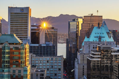 Modern buildings in city against sky during sunset