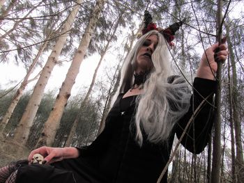 Low angle view of woman in witch costume at forest