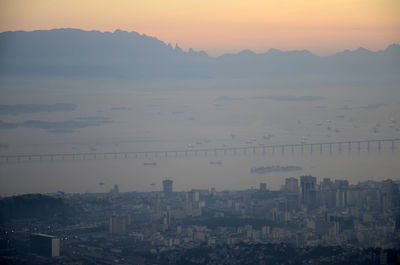 Rioniteroi bridge in sea against silhouette mountains