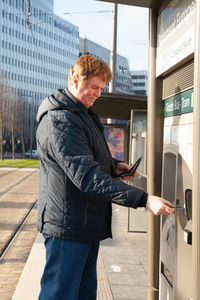 Side view of man using mobile phone in city