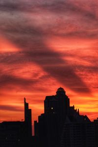 Silhouette of buildings against cloudy sky during sunset
