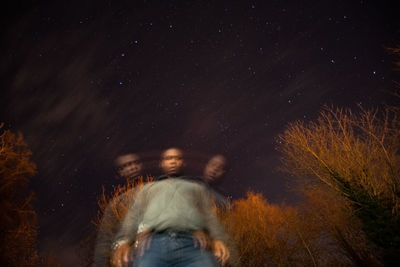 Blurred motion of man against trees and sky at night