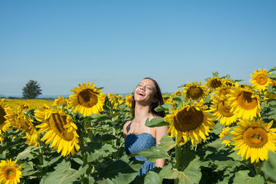 Happy woman in sunflower field against blue sky