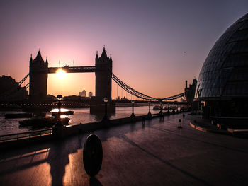 Silhouette tower bridge against sky during sunset in city