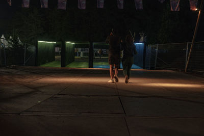 Rear view of woman walking on footpath at night