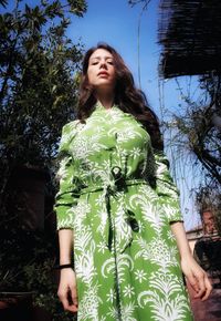 Portrait of young woman standing against trees