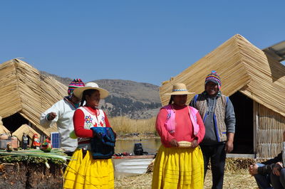 Rear view of people standing on mountain against clear sky