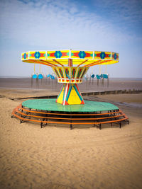 A closed and abandoned seaside fair ground carrousel on the beach at cleethorpes on a sunny day.