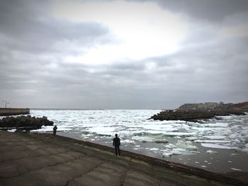 People at beach against sky