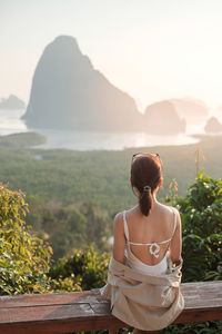 Rear view of woman looking at mountains against sky