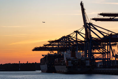 Commercial dock by sea against sky during sunset