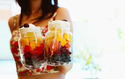 Unrecognizable woman holding and showing a jar with chopped fruit salad