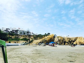 People on beach by building against sky