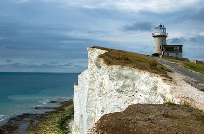 Lighthouse by sea against sky