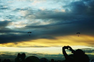 Silhouette of bird flying over cloudy sky
