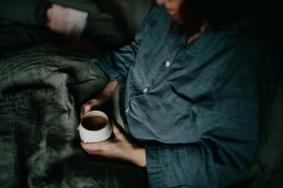 Midsection of woman holding coffee at home